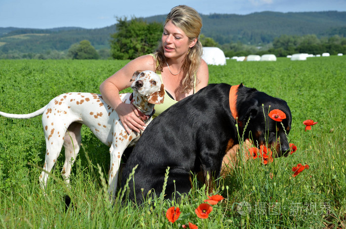 年轻女人在摆姿势与她在绿色的草原上的大狗