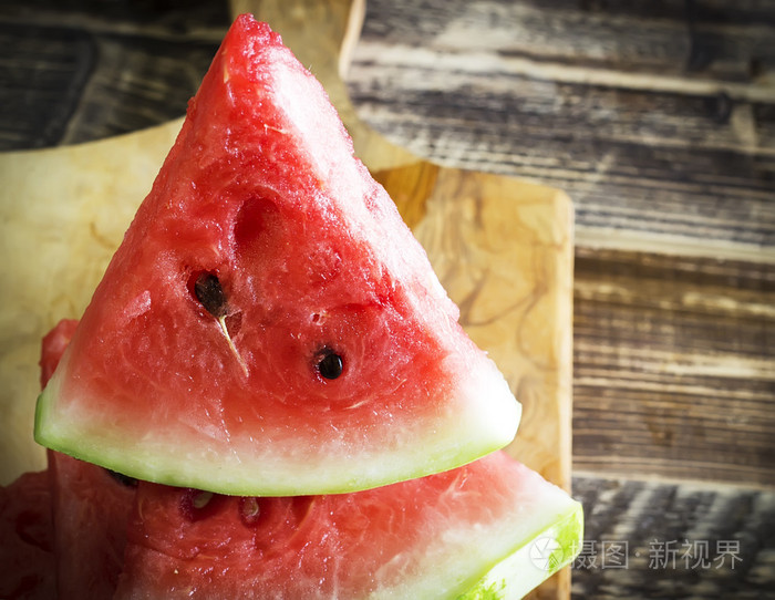 大块三角形的西瓜厨具板和木质的背景