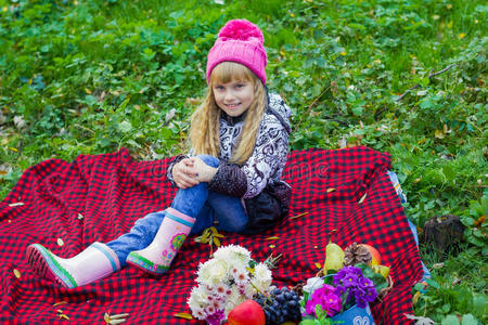 戴着粉红色帽子的漂亮的小婴儿。 漂亮的孩子坐在红色格子上。