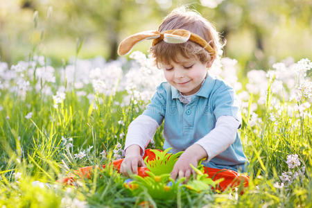 可爱快乐的小男孩戴着复活节兔子耳朵在春天绿色