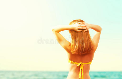 美丽的快乐女人穿着黄色泳衣在海滩上