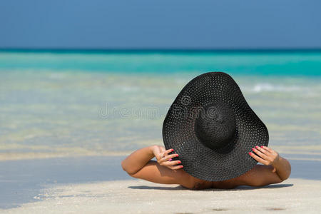 戴帽子的美女躺在热带海滩上