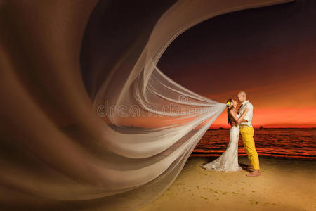 新娘和新郎在热带海滩上，背景是夕阳