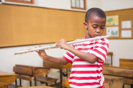 可爱的学生在教室里吹长笛