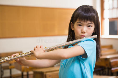 可爱的学生在教室里吹长笛