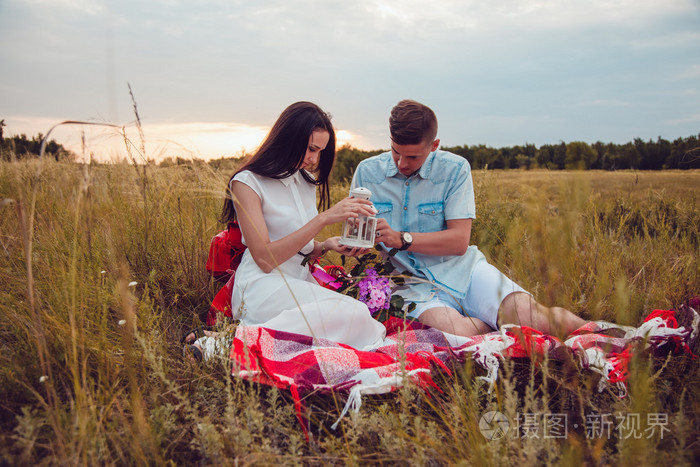 漂亮年轻幸福恩爱的夫妻在野餐会上躺在阳光灿烂的夏天一天享受和休息