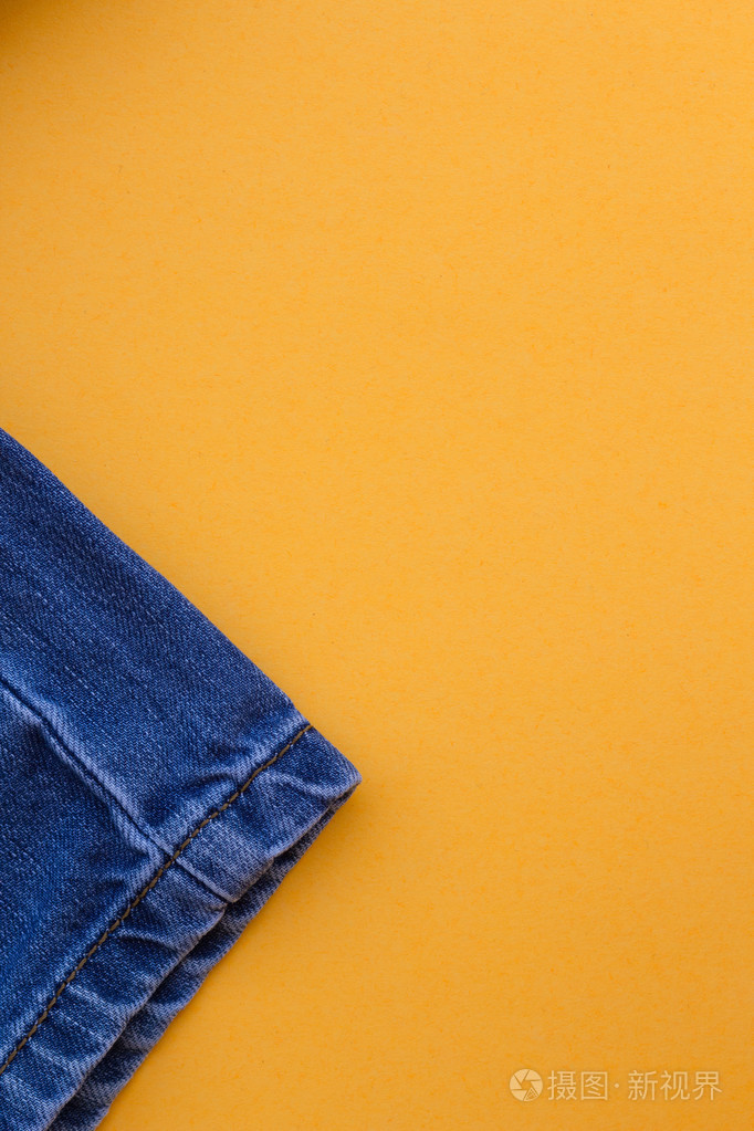 在黄色背景蓝色牛仔裤