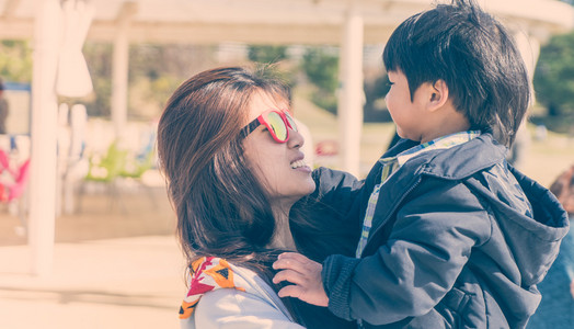 妈妈举起孩子妈妈高兴地举起她的孩子,复古色调照片