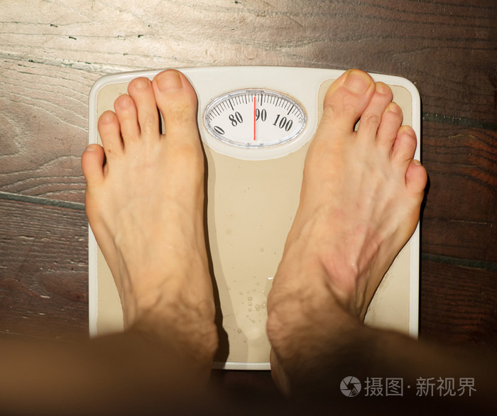 男人站在浴室磅秤上约90公斤
