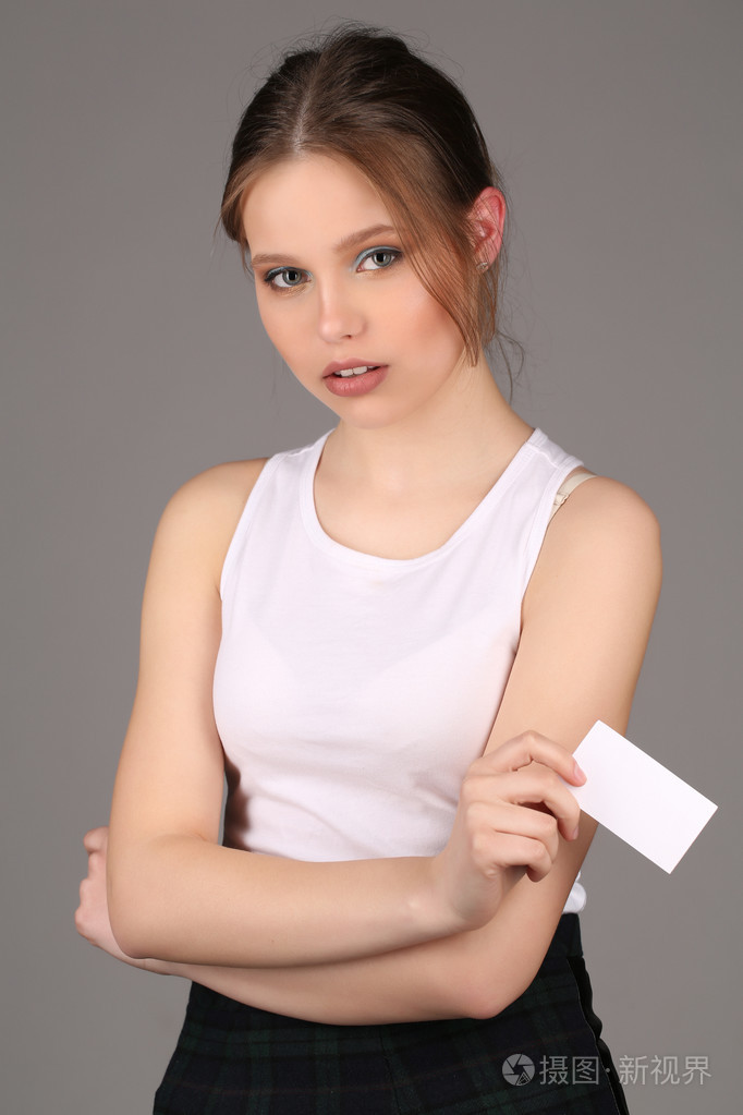 手里拿着白色卡片的女孩快关门灰色背景