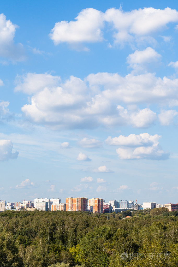 白云在蔚蓝的天空在城市和绿色的树林