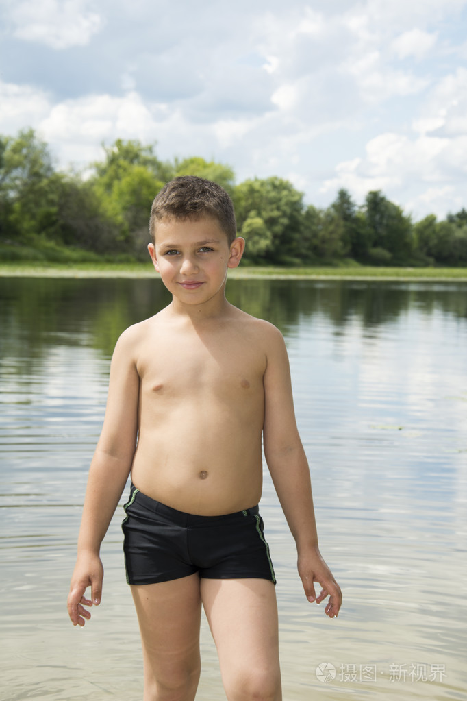 夏天阳光灿烂的日子的小男孩站在水中