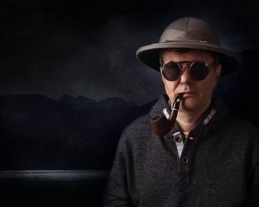 老男人吸烟管头盔的烟斗的男人照片