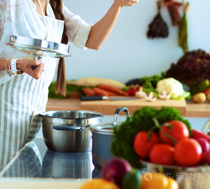 烹饪的女人在厨房里用木勺