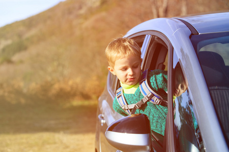 快乐的小男孩乘汽车旅行性质照片