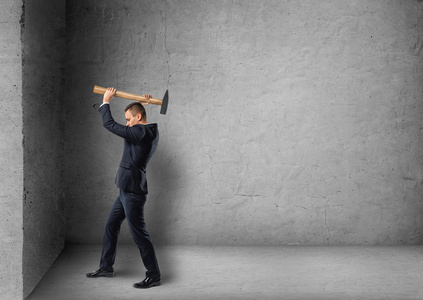 大的锤子击打墙面砖锤子的力量站在又脏又臭的墙前用锤子的商人商人用