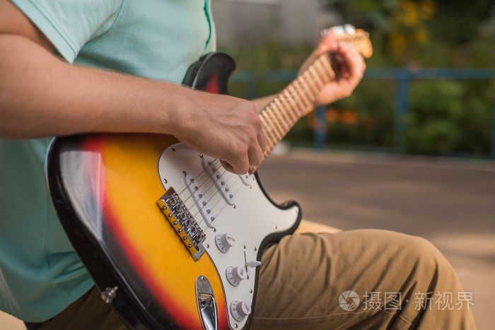 年轻人坐在弹吉他特写的时髦
