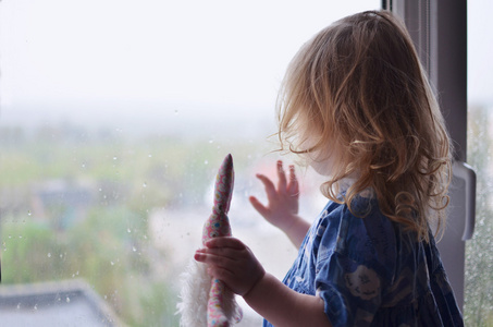 儿童女孩看着窗户上的雨滴图片