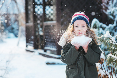 快乐的孩子女孩玩雪的后院,下雪的冬天一直走在花园里做雪球照片