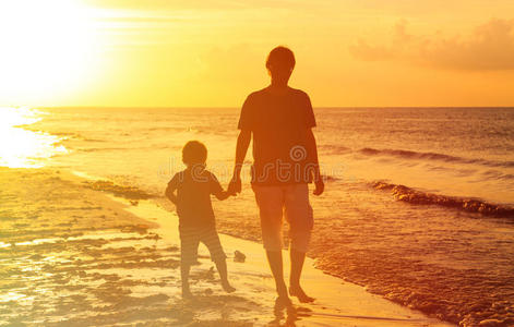 父子在日落的海上散步