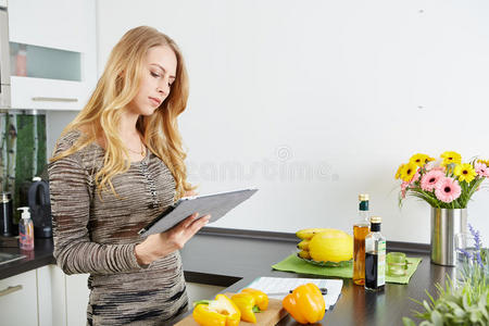 金发女人用平板电脑做饭