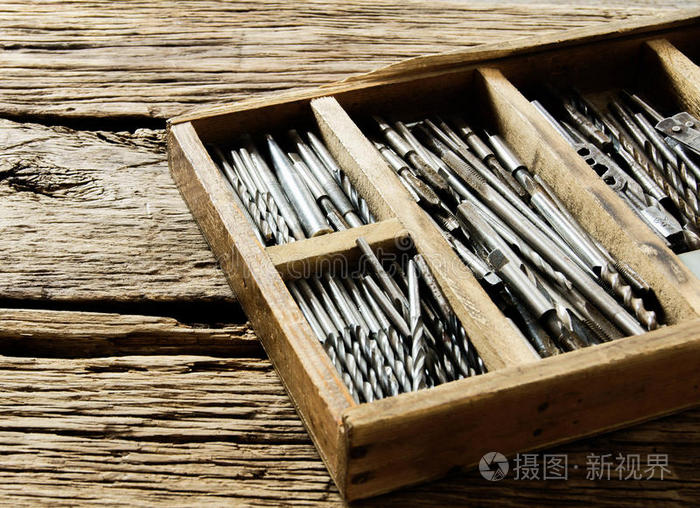 木制背景上有钻头的盒子