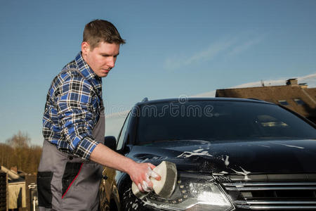 一个年轻人正在街上清理他的车