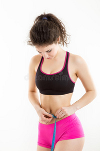 健身女孩测量她完美的身材美丽的腰部。