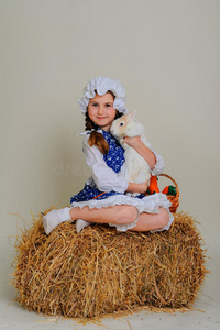 干草上的女孩拥抱复活节兔子。