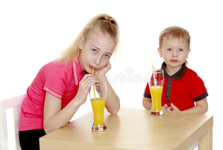 哥哥姐姐坐在桌子旁喝果汁