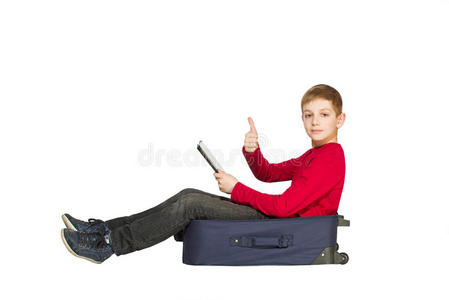 男孩坐在旅行袋上，拿着平板鞋，竖起大拇指
