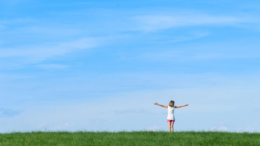 快乐的小女孩,站在蓝色的天空背景上的字段照片