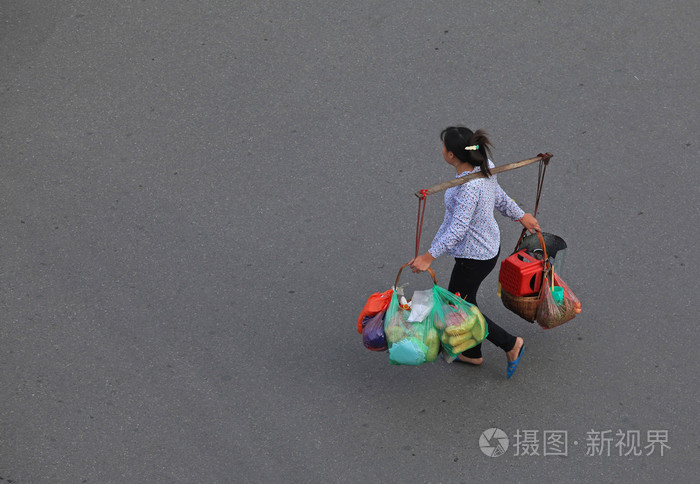 购物后的女人背着一根棍子背着很多包裹