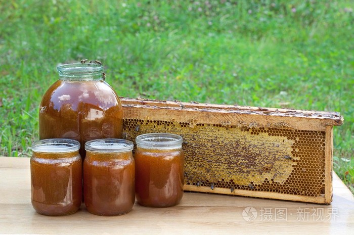 新鲜的蜂蜜，放在罐子里木制的桌子上