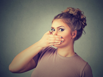 受惊的年轻女人,用一只手捂着嘴照片