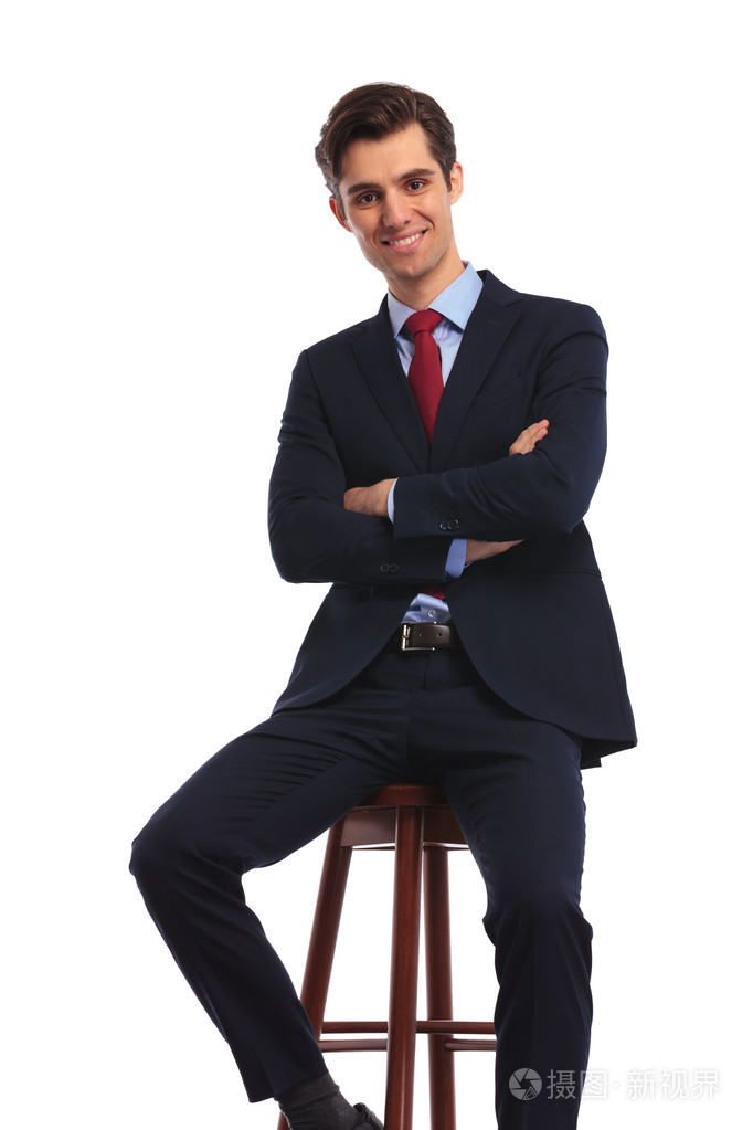 快乐的年轻商人双手交叉坐着