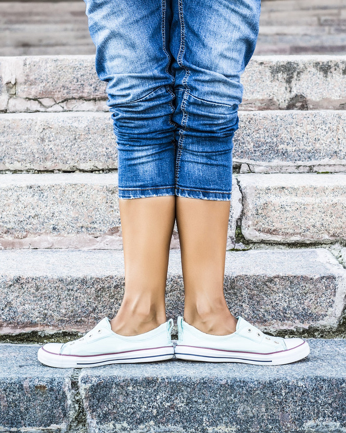 脚穿舞足尖鞋,运动鞋背景下的石阶.性感的女性腿