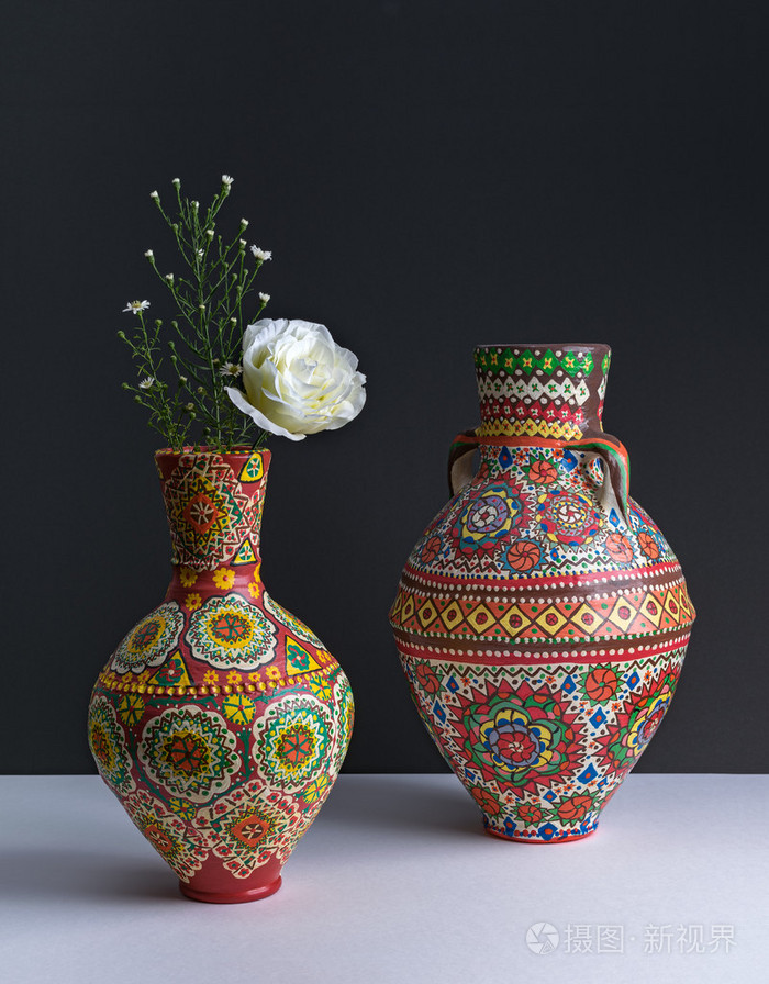 与黄色的花蕊,在黑色背景上的两个多彩陶器花瓶