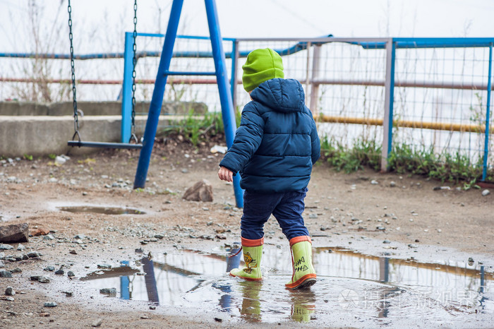 蹒跚学步的男孩在水坑里跳