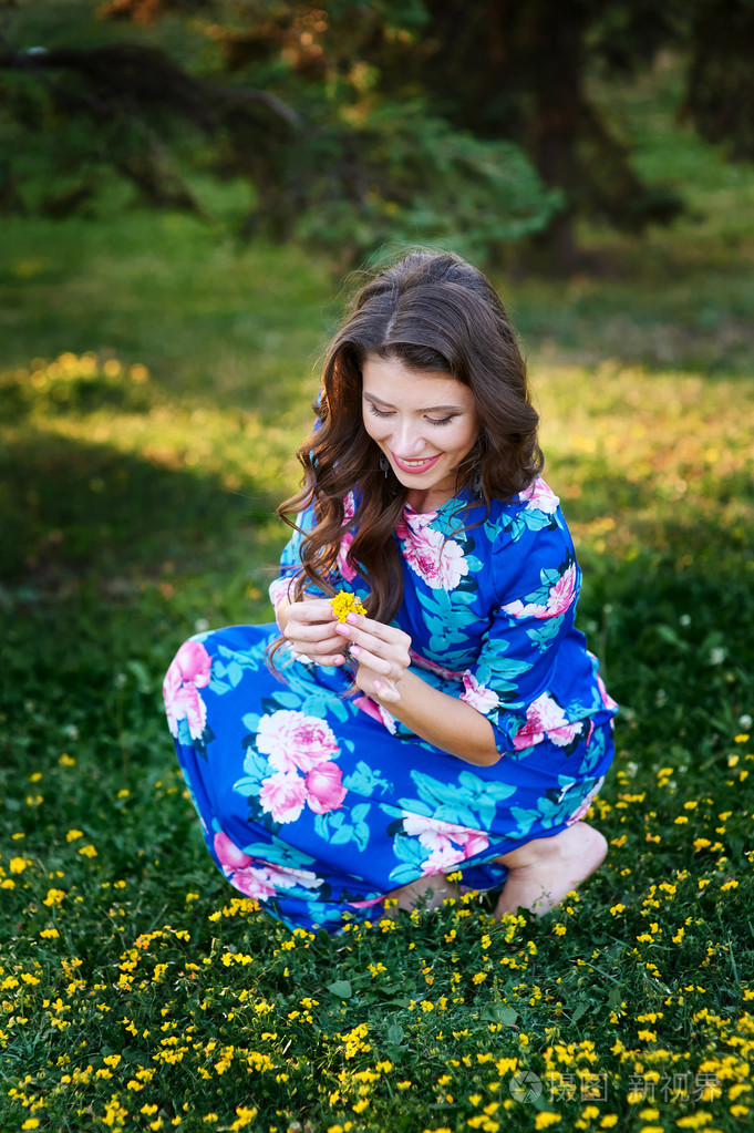 美丽的女人在一块草地上摘花黄色