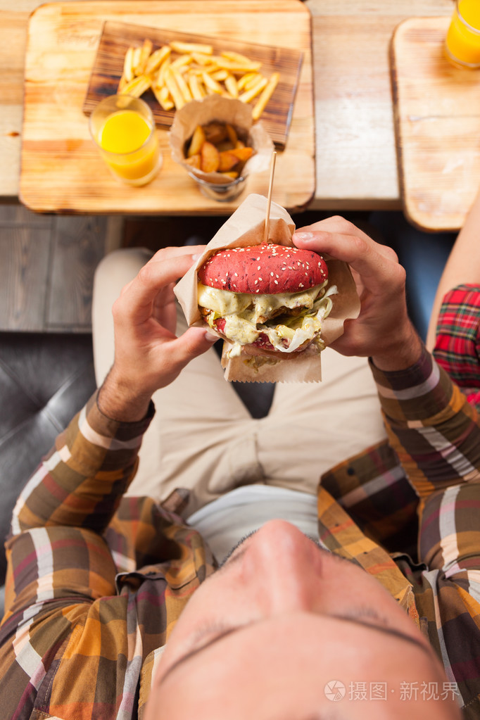 年轻男子牛肉汉堡顶视角照片-正版商用图片1q478e-摄图新视界