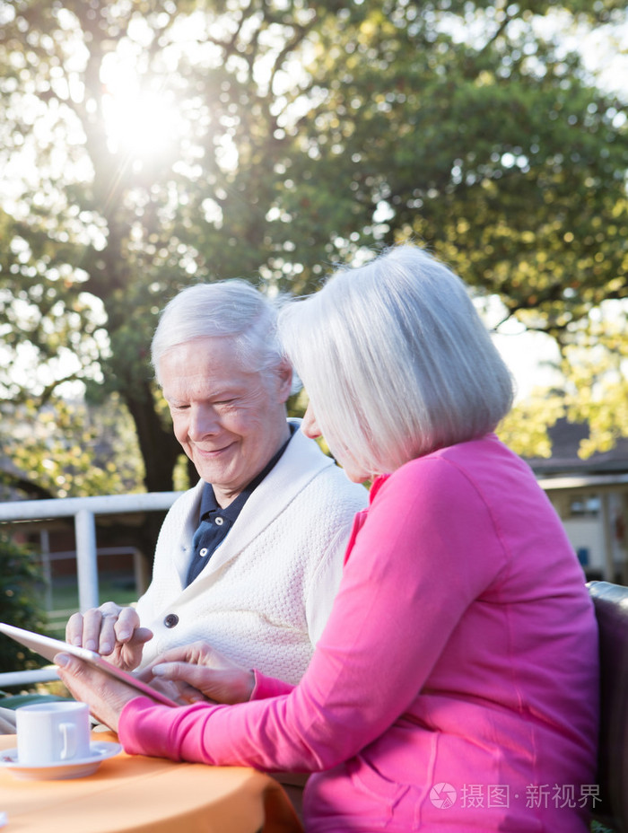 使用平板电脑放松户外的快乐退休的夫妇