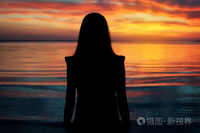 年轻漂亮的女孩在夕阳的热带海滩上的轮廓自然夏天背景