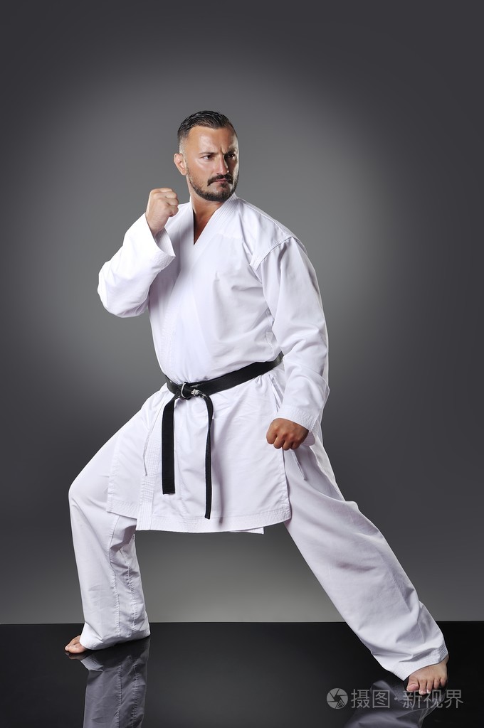 做卡塔在灰色的背景上的英俊年轻男性空手道