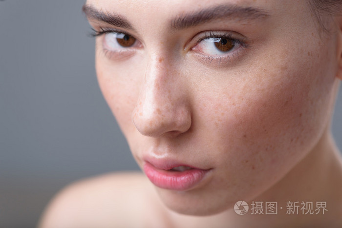 在灰色的背景上的雀斑有魅力的女人肖像