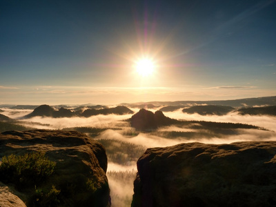 明亮的橙色破晓.砂岩悬崖上面在萨克森瑞士深迷雾笼罩的山谷.