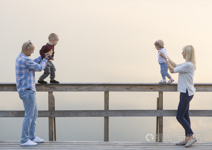 幸福的家庭,两个父母和孩子,一个男孩子,女婴,在河码头上有好的时间.