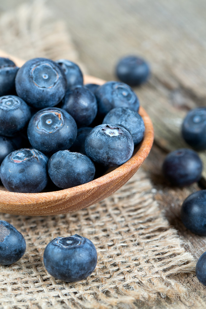 在木桌木汤匙里的新鲜蓝莓