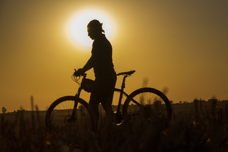 日落和剪影背光骑自行车的人图片