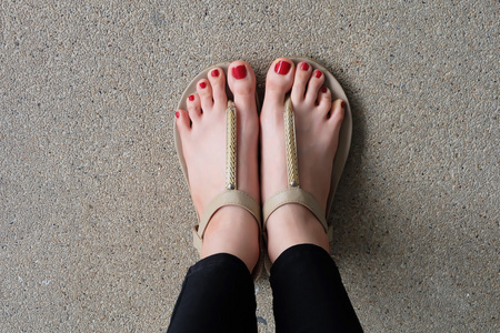 拖鞋走路女性脚穿着拖鞋或拖鞋户外红色指甲照片
